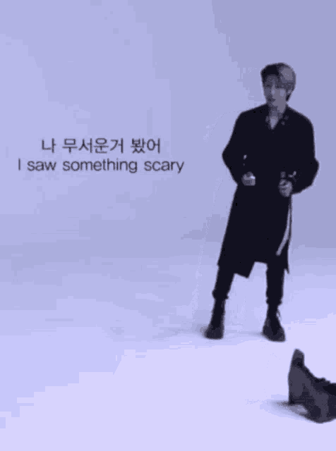 a man in a black coat is standing in front of a sign that says something scary