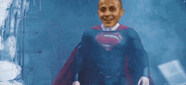 a man in a superman costume is standing in front of a blue wall