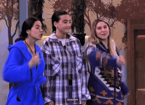 three women wearing blue robes and plaid shirts are standing next to each other