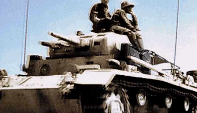 two soldiers are sitting on top of a tank with a blue sky in the background