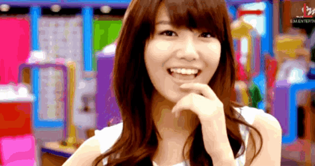 a woman is smiling in front of a sign that says ' s.m.entertainment ' on it