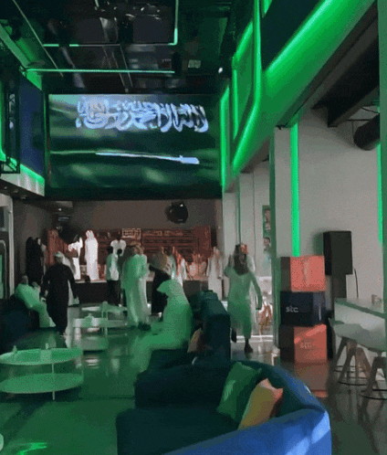 a group of people standing in front of a large screen that says ' saudi arabia '