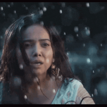 a woman is standing in the rain and looking at the camera with a surprised look on her face .