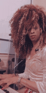 a woman with curly hair playing a keyboard