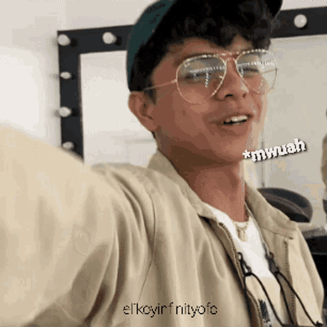 a young man wearing glasses and a hat is taking a selfie with a caption that says mwuah