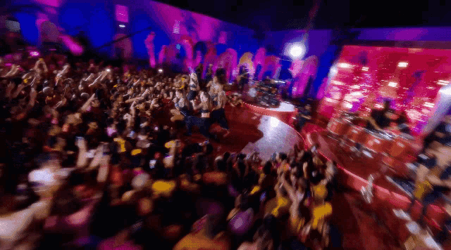a blurry picture of a crowd at a concert with a pink background