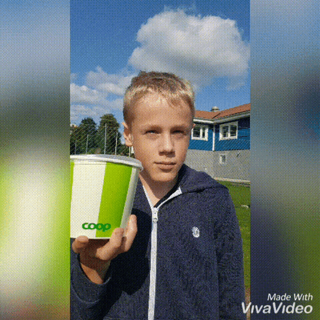 a young boy is holding a coop cup in his hand