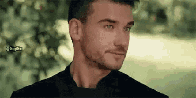 a close up of a man 's face with a beard and green eyes looking at the camera .