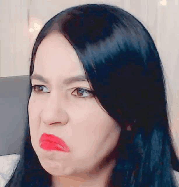 a woman with long black hair is making a funny face with red lipstick .
