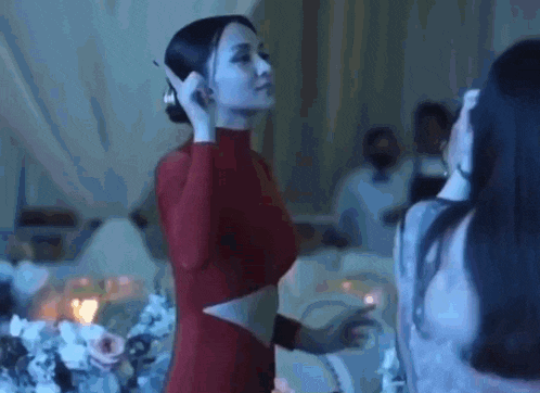 a woman in a red dress is talking on a cell phone while standing next to another woman .