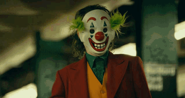 the joker is wearing a clown mask and a red suit