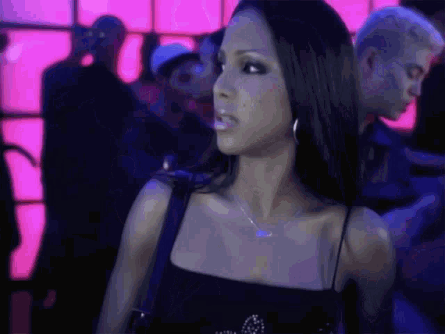 a woman in a black top is standing in a crowd of people .