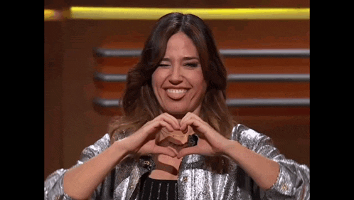 a woman is making a heart shape with her hands while smiling .
