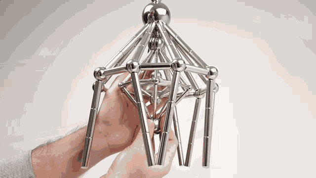 a person is holding a metal structure in their hand