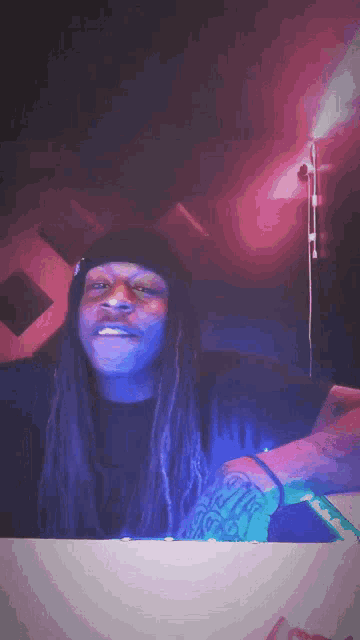 a man with dreadlocks wearing a black beanie and a tattoo on his arm