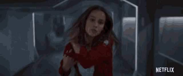 a woman in a red jacket with netflix written on the bottom right
