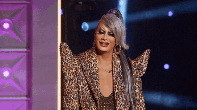 a drag queen with gray hair and a leopard print jacket
