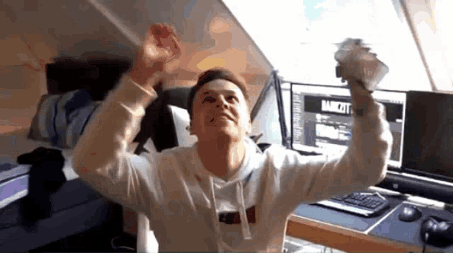 a man in a white tommy hilfiger sweatshirt holds up his arms in the air
