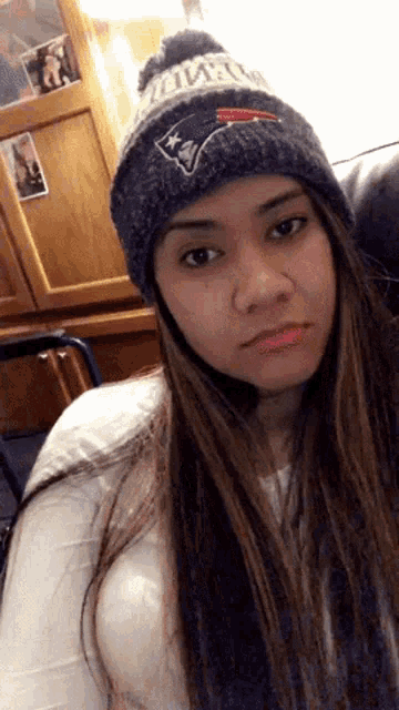 a woman wearing a patriots beanie is sitting on a couch
