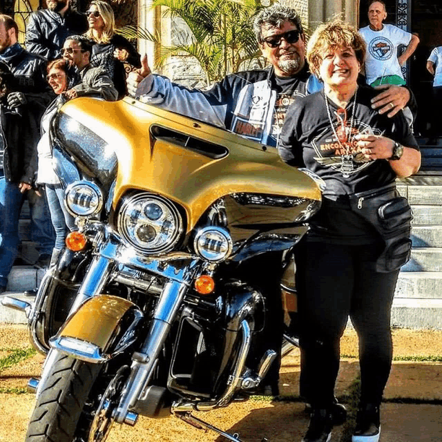 a man and a woman standing next to a motorcycle