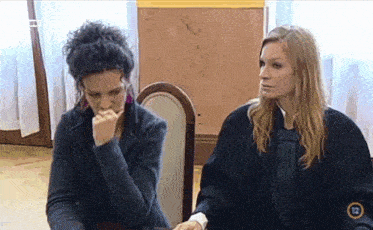 two women are sitting at a table and one of them has the number 12 on her shirt