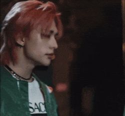 a young man with red hair is wearing a green jacket .