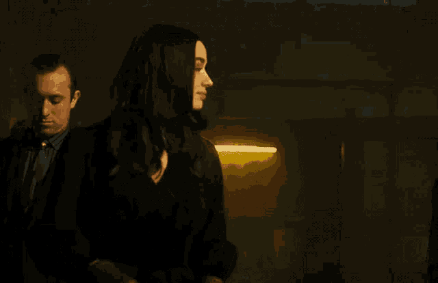 a woman in a black suit is standing next to a man in a suit and tie .