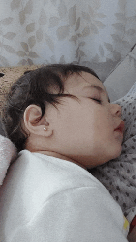 a baby with ear piercings is sleeping on a bed