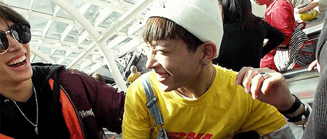 a man wearing a yellow shirt and a white hat is laughing with another man