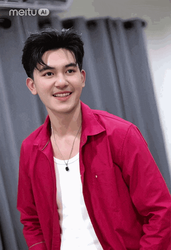 a young man wearing a red shirt and a white tank top smiles in front of a curtain with meituan written on the bottom