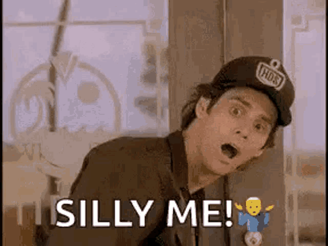 a man in a baseball cap is standing in front of a window and saying `` silly me ! ''