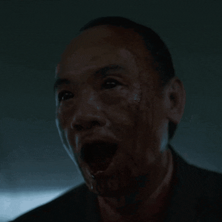 a man with blood on his face is screaming with his mouth wide open .