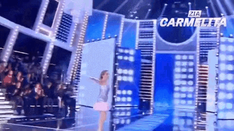 a woman in a pink dress is on a stage with zia carmella written on the bottom right
