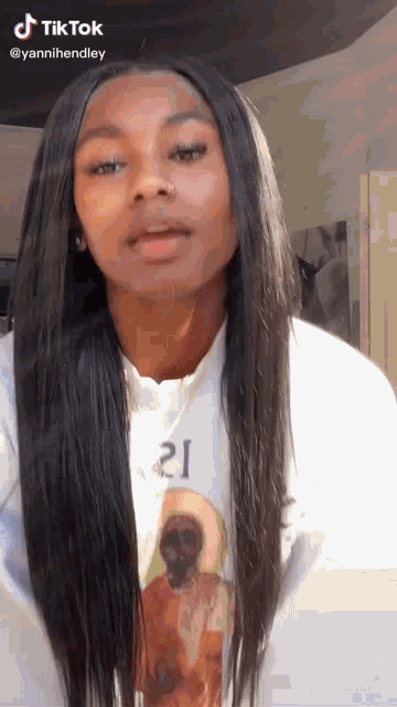 a woman with long hair is wearing a white sweatshirt with a picture of a woman on it .