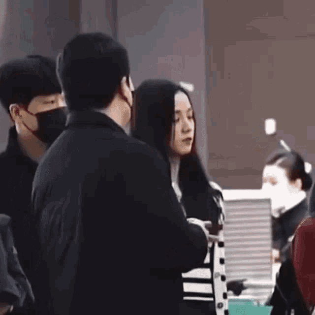 a man and a woman are standing next to each other in an airport . the woman is wearing a mask .