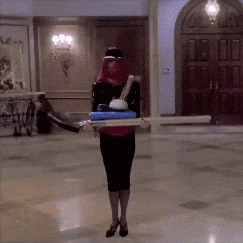 a woman wearing a red mask is holding a tray of cleaning supplies