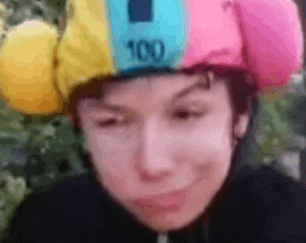 a person wearing a colorful hat with the number 100 on it is smiling .