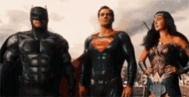 batman , superman and wonder woman are standing next to each other in a row .