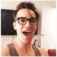a man wearing glasses and a tank top is taking a selfie