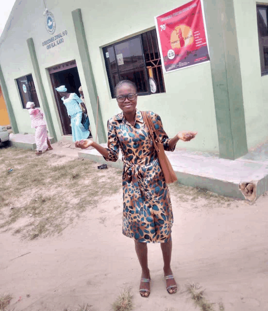 a woman stands in front of a green building that says ' gospel church ' on it