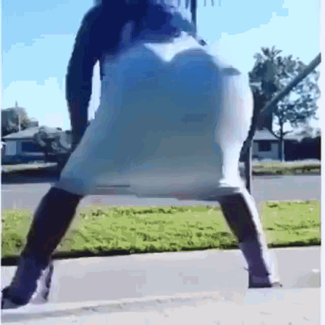 a woman in a white dress is dancing on the sidewalk .