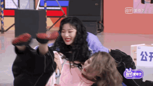 a couple of girls are laying on the floor with a sign that says ' iqiyi ' on the bottom