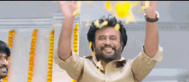 a man with a beard is smiling and raising his arms in the air .