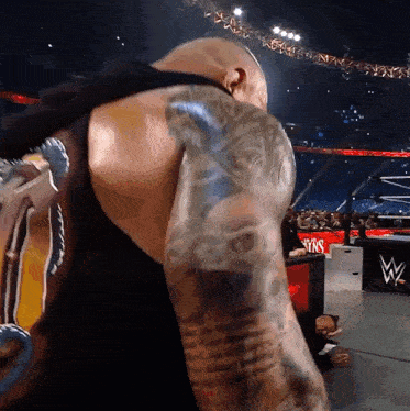 a man with a tattoo on his arm is standing in front of a sign that says ' wins '