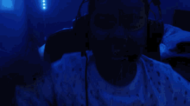 a person wearing headphones in a dark room with blue lights behind them