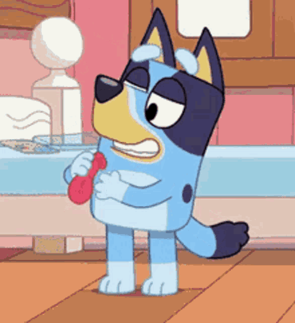 a cartoon dog is standing on a wooden floor and holding a red object .