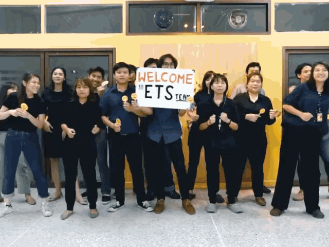 a group of people holding up a sign that says " welcome to the ets team "