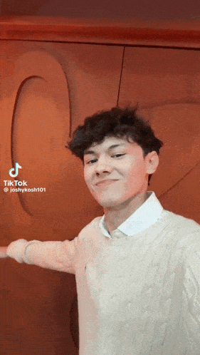 a young man is taking a selfie with his arm outstretched in front of a wall with a heart carved into it