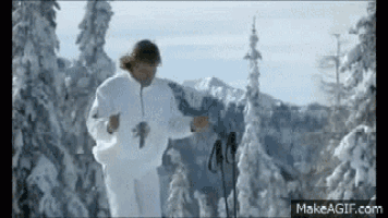 a man in a white jacket is walking through the snow .