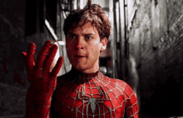 a man in a spiderman costume is holding his hand up